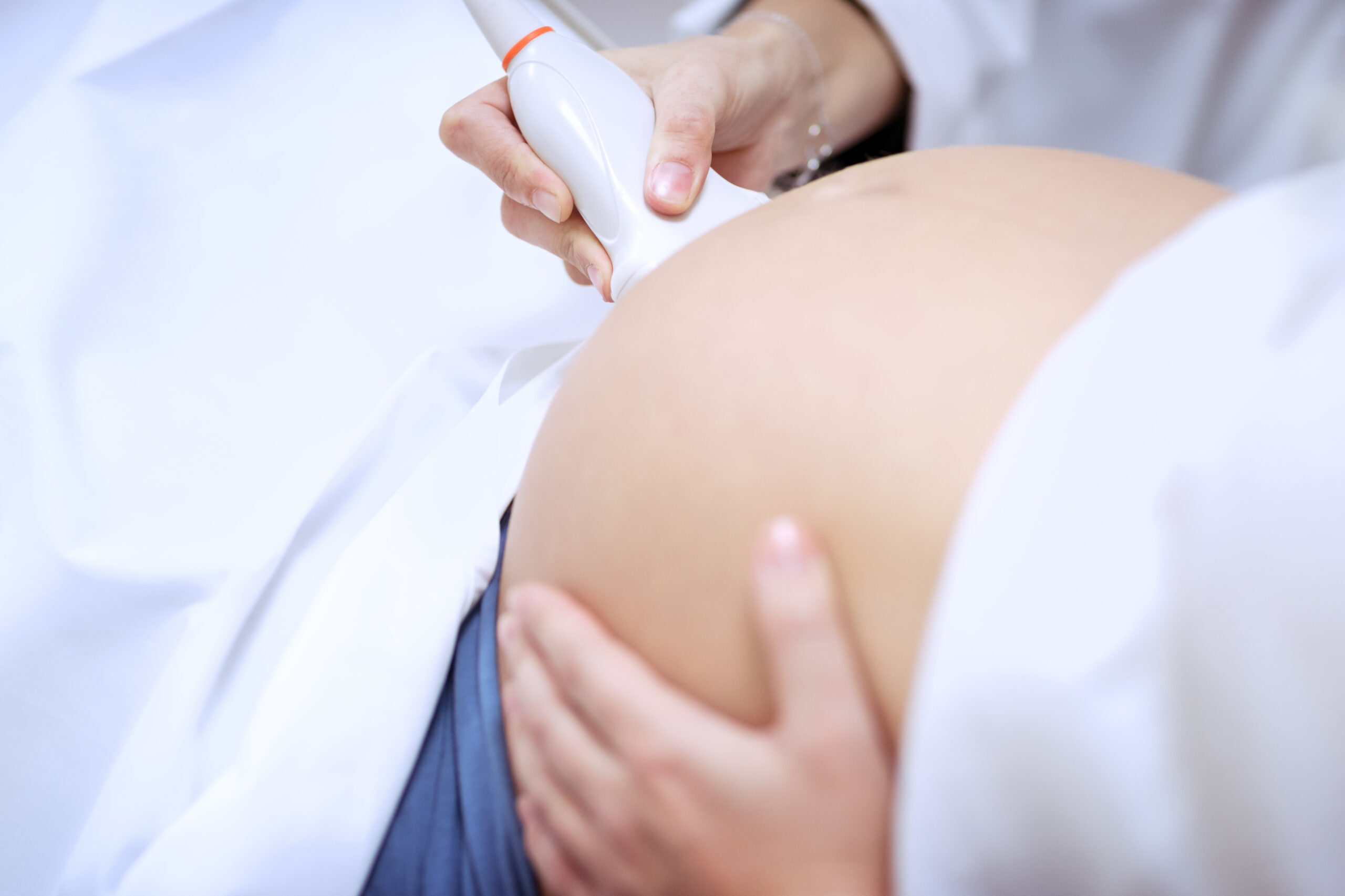 Doctor making ultrasound scanning for pregnant woman, ultrasound is safe and painless, closeup photo of a women's abdomen on third trimester, body part, conceptual photo of healthy pregnancy